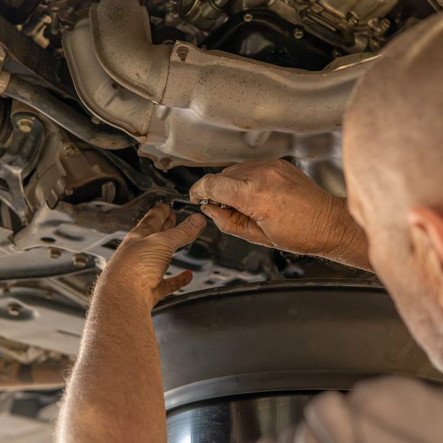 Mechanic working on the underside of a car on the hoist