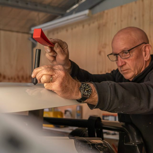Paint protection film being applied to a bonnet with a squeegee