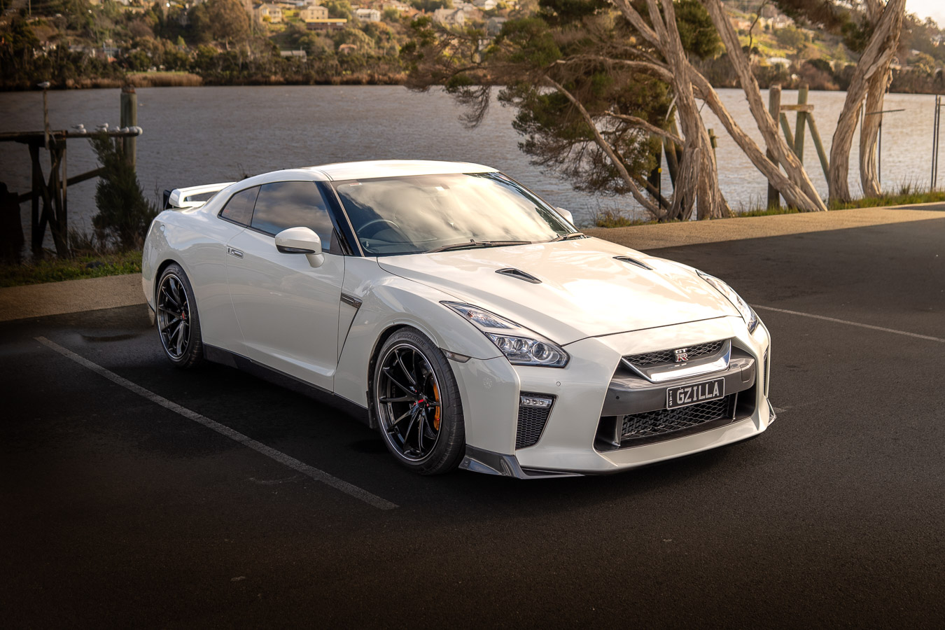 White Nissan GT-R front three-quarter view parked beside a riverbank