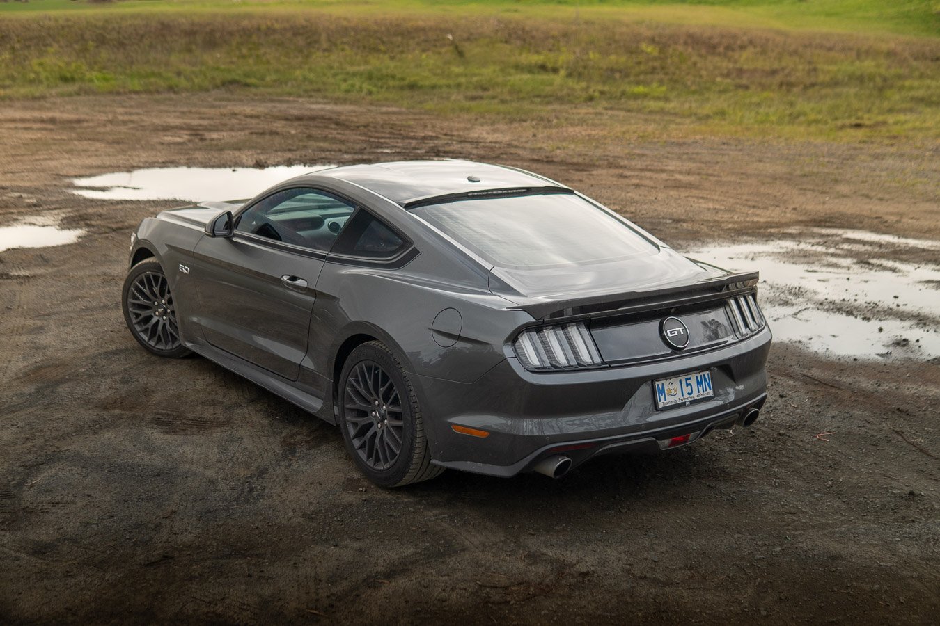 Grey Ford Mustang GT rear three-quarter view beside puddles