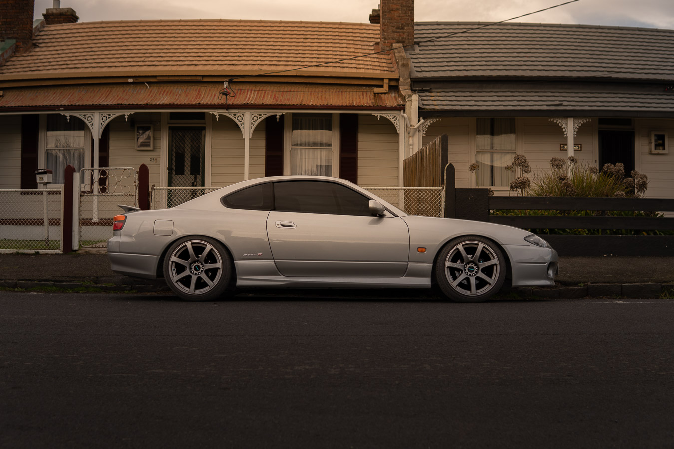 Silver Nissan Silvia S15 side profile in front of heritage homes